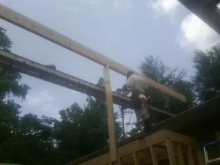 Carpenter setting a ridge beam over a new addition frame — Ice Dam Removal by Roofing Brothers in Nielsville