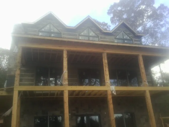 Dormers and porch framing on a large log home under construction — Roof Coating work by our crew in Nielsville