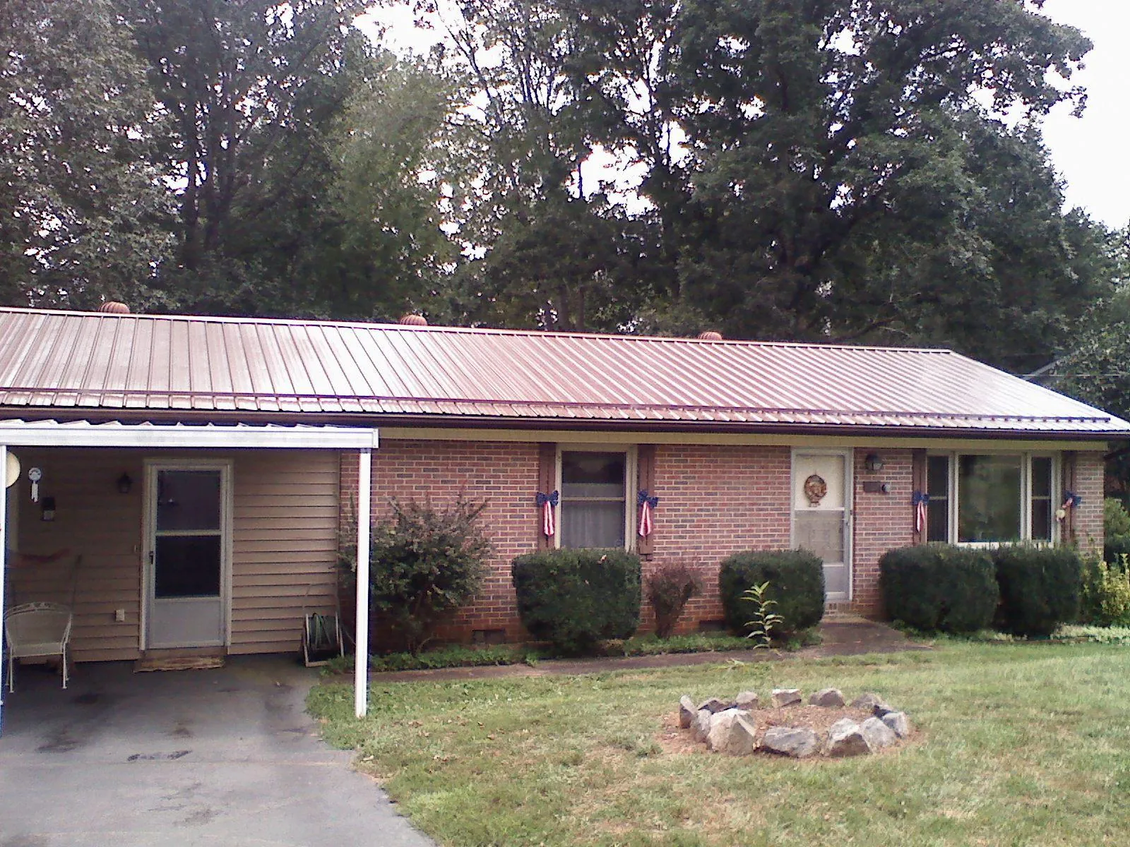 Bronze metal roof and carport on a brick ranch home — Roof Repair work by our crew in Nielsville