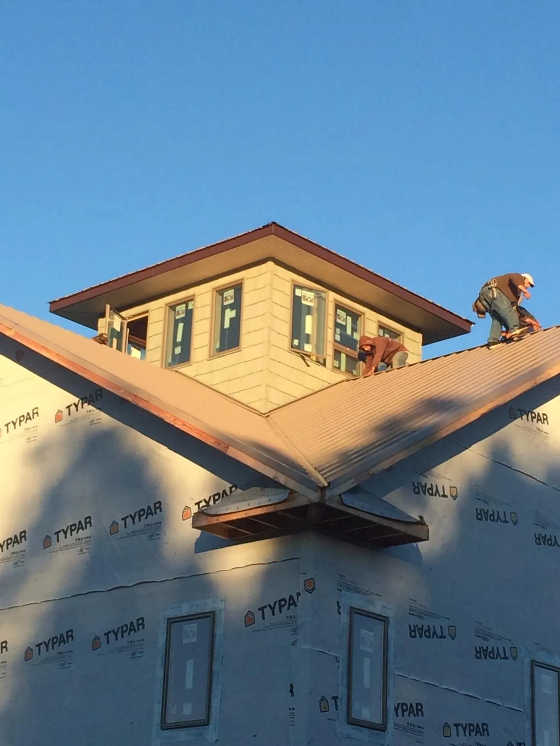 Roofers working around a rooftop cupola on a new metal roof at sunset — Roof Waterproofing in Nielsville by Roofing Brothers